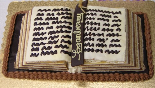 Picture of a cake shaped and iced to look like an open book with icing writing and a book mark that says Loganberry.